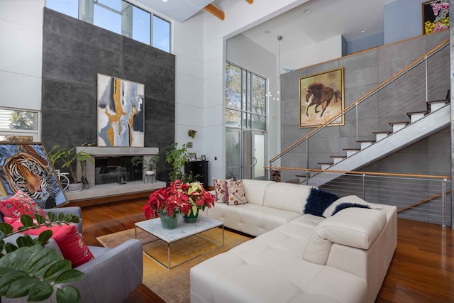 living room with hardwood / wood-style floors, a towering ceiling, and a healthy amount of sunlight