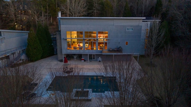 rear view of property featuring a pool and a patio