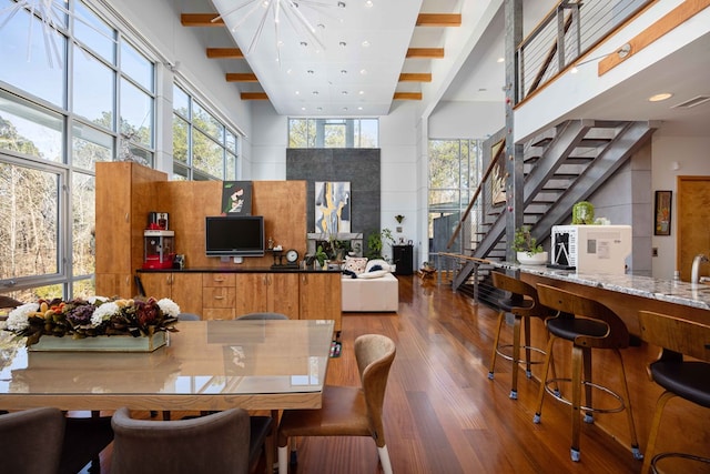 dining space featuring hardwood / wood-style floors, beam ceiling, and a high ceiling