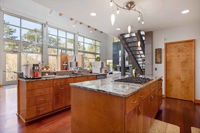 kitchen featuring appliances with stainless steel finishes, decorative light fixtures, a kitchen island, and dark hardwood / wood-style floors