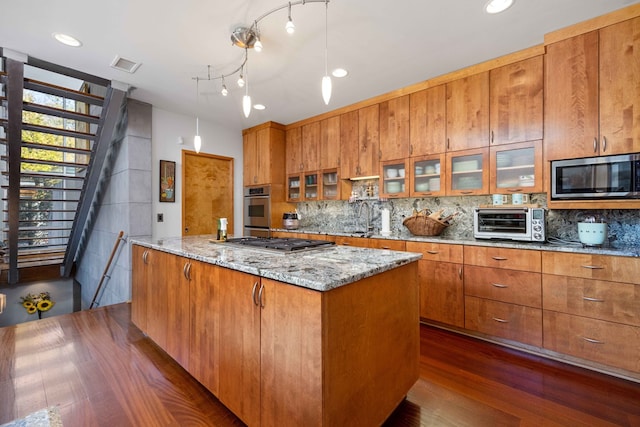 kitchen featuring decorative backsplash, decorative light fixtures, a center island, and stainless steel appliances