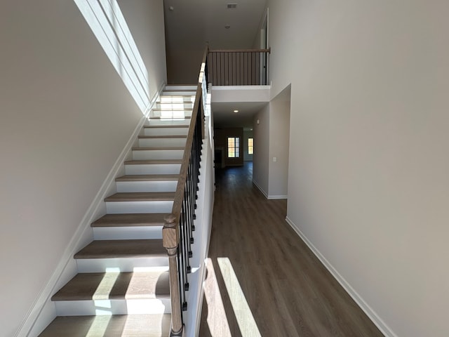 staircase featuring hardwood / wood-style floors and a high ceiling