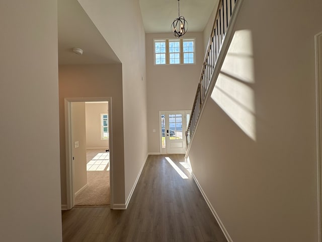 hall with a high ceiling, dark hardwood / wood-style flooring, and a notable chandelier