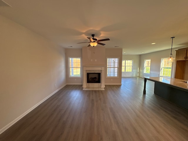 unfurnished living room with a premium fireplace, dark hardwood / wood-style flooring, and ceiling fan