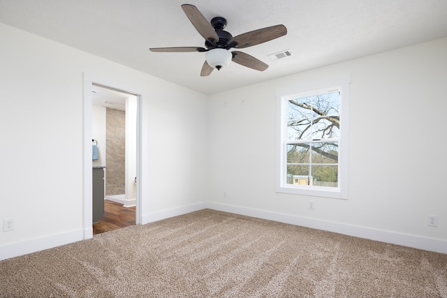 empty room featuring visible vents, dark carpet, and baseboards