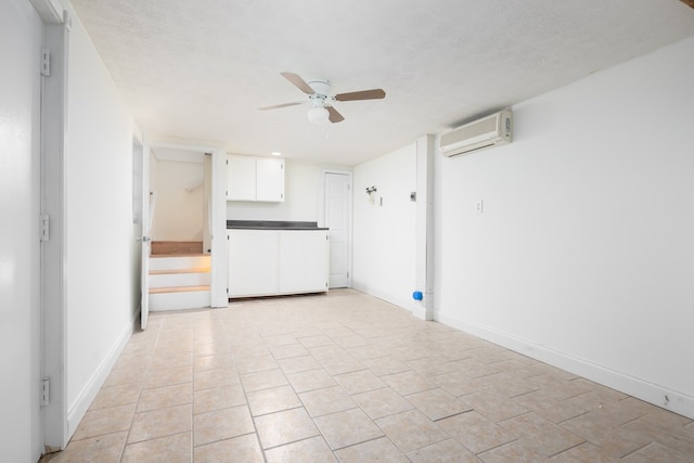 spare room featuring a wall mounted air conditioner, ceiling fan, a textured ceiling, and baseboards