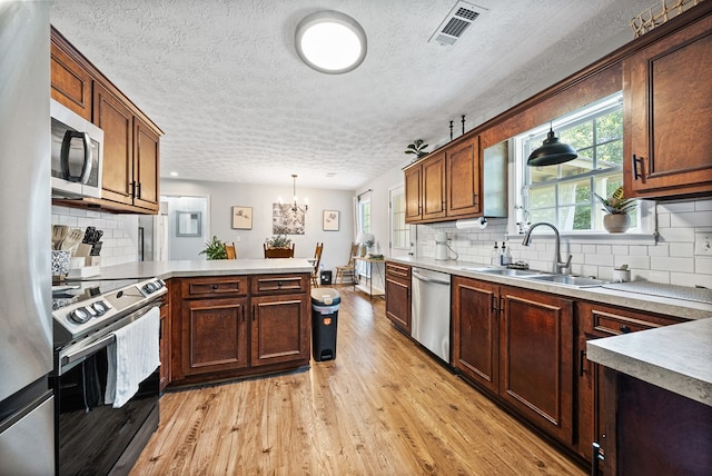 4607 N Tillery Dr, Phenix City, AL 36870 - kitchen with appliances with stainless steel finishes, a peninsula, a textured ceiling, light wood finished floors, and decorative light fixtures