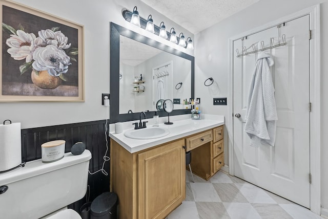 4607 N Tillery Dr, Phenix City, AL 36870 - bathroom featuring a textured ceiling, vanity, and a wainscoted wall