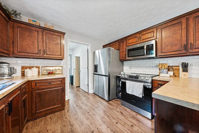 4607 N Tillery Dr, Phenix City, AL 36870 - kitchen with appliances with stainless steel finishes, light wood-style floors, light countertops, a textured ceiling, and tasteful backsplash