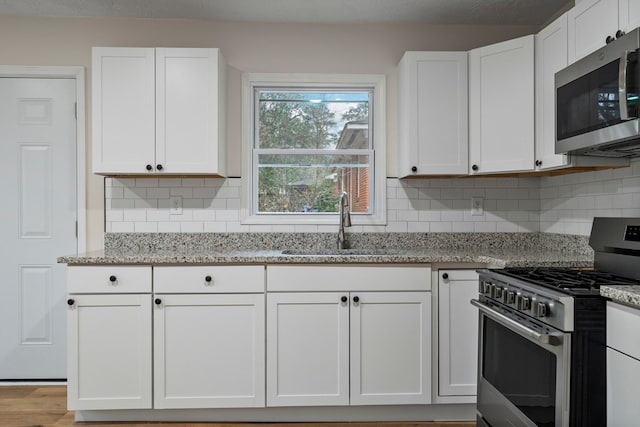 1474 Brewer Ave, Columbus, GA 31903 - kitchen with sink, appliances with stainless steel finishes, white cabinetry, tasteful backsplash, and light stone countertops