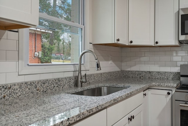 1474 Brewer Ave, Columbus, GA 31903 - kitchen with white cabinetry, appliances with stainless steel finishes, light stone countertops, and sink