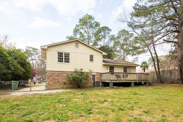 rear view of house with a lawn, a deck, brick siding, and fence