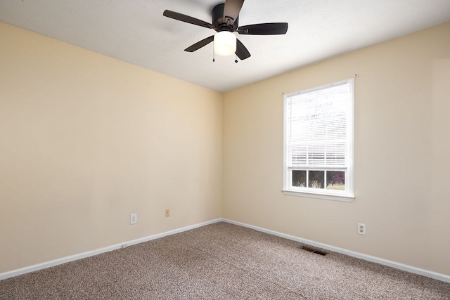 carpeted spare room with visible vents, baseboards, and ceiling fan