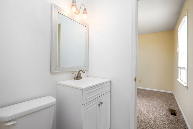 half bath with visible vents, toilet, vanity, and baseboards