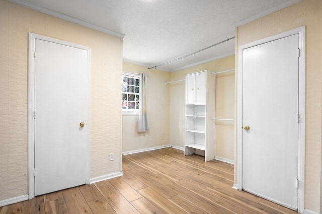 unfurnished bedroom featuring baseboards, light wood-style flooring, and crown molding