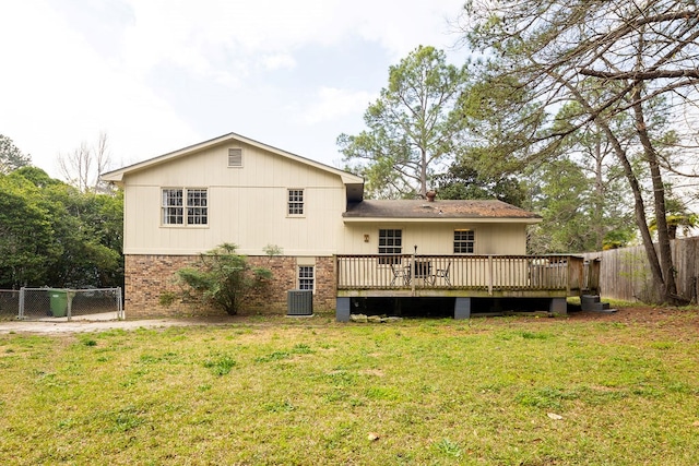 rear view of house with a deck, a yard, fence, and brick siding