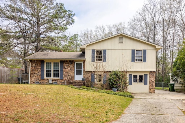 tri-level home with brick siding, a front yard, and fence