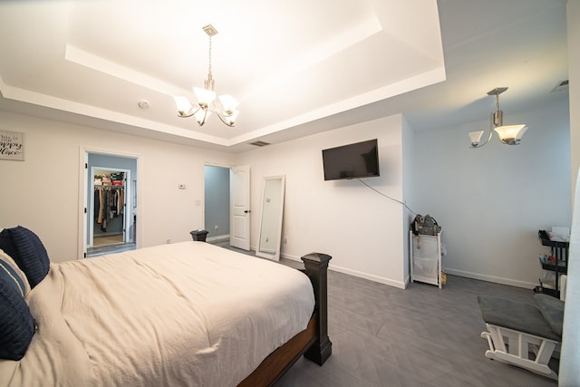 carpeted bedroom featuring an inviting chandelier, a raised ceiling, a spacious closet, and a closet