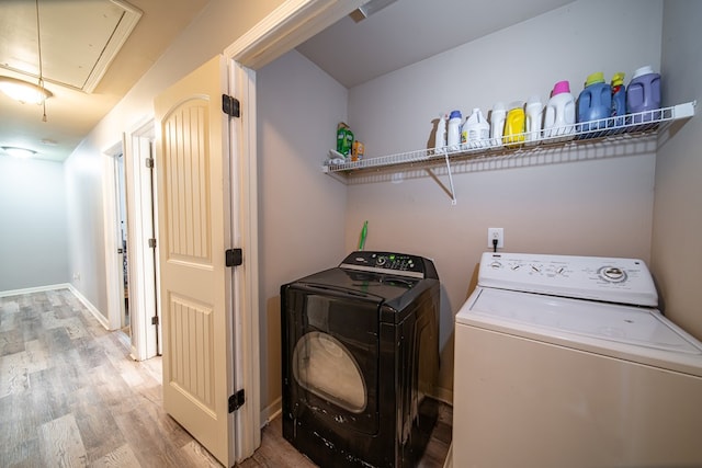 clothes washing area with washing machine and clothes dryer and hardwood / wood-style flooring