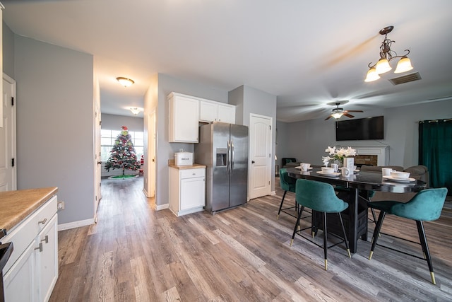 kitchen featuring pendant lighting, white cabinets, light hardwood / wood-style flooring, ceiling fan, and stainless steel fridge with ice dispenser