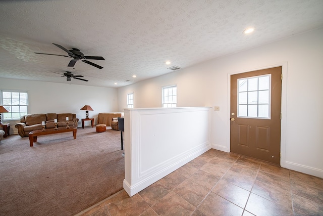 interior space with carpet flooring, a textured ceiling, and ceiling fan