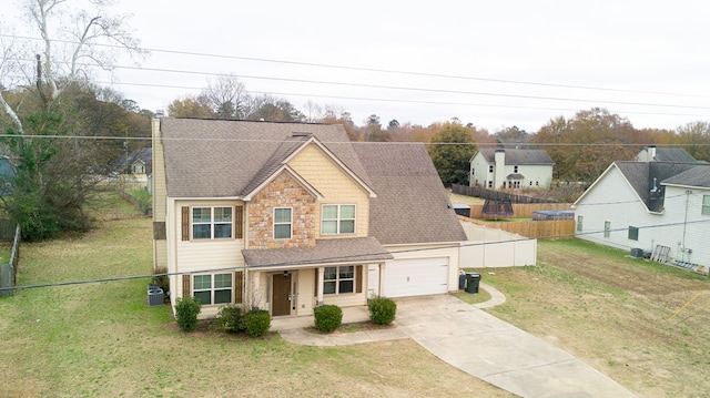 view of front of home with covered porch, a garage, a front lawn, and central air condition unit