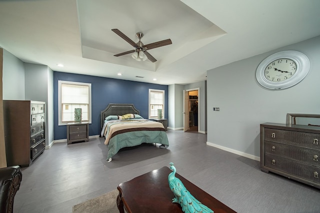 bedroom with ceiling fan, a raised ceiling, hardwood / wood-style floors, a walk in closet, and a closet