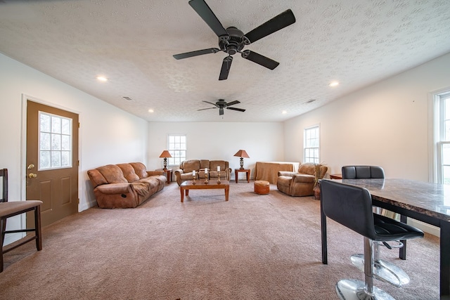 carpeted living room with ceiling fan and a textured ceiling