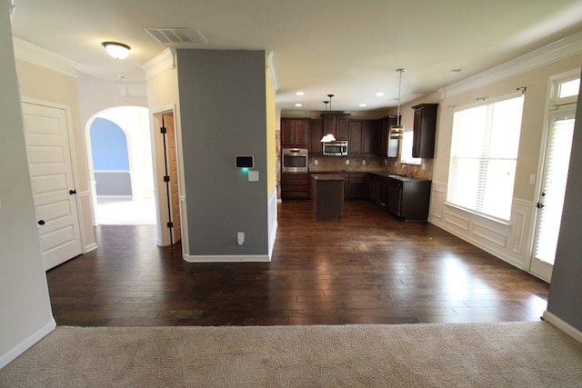 kitchen featuring stainless steel appliances, arched walkways, visible vents, and ornamental molding