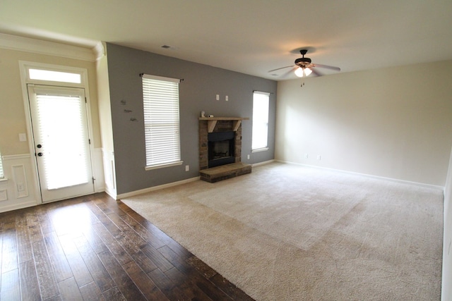 unfurnished living room featuring a stone fireplace, baseboards, and ceiling fan