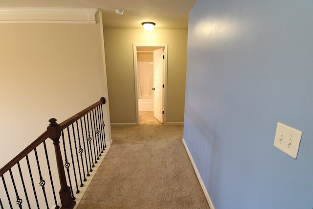 hallway with an upstairs landing, baseboards, and light carpet