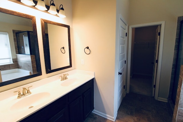 bathroom with double vanity, a walk in closet, baseboards, and a sink