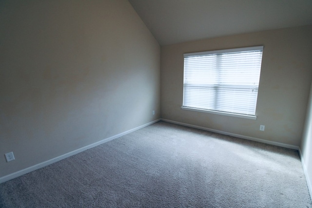 empty room with baseboards, lofted ceiling, and carpet floors