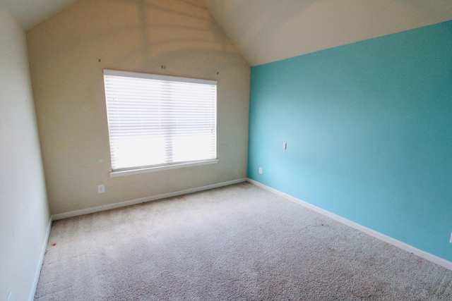 empty room featuring vaulted ceiling, baseboards, and carpet floors