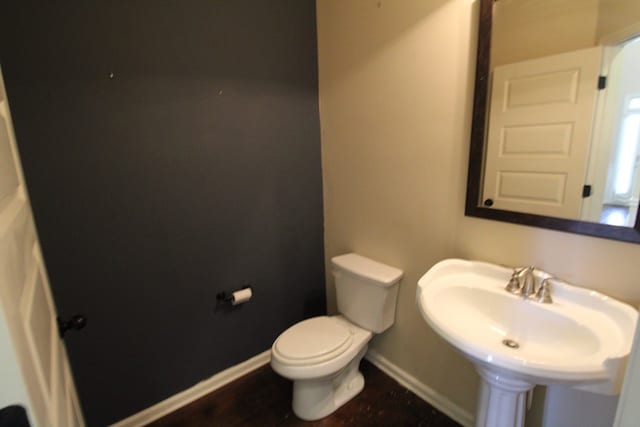 half bath featuring a sink, baseboards, and toilet