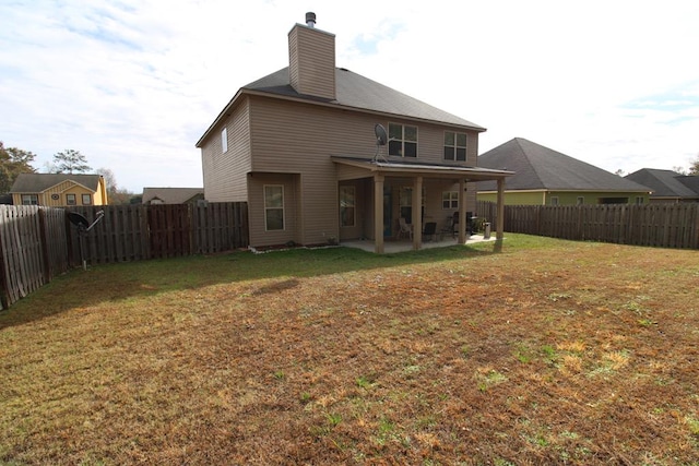 back of property featuring a lawn, a fenced backyard, a chimney, and a patio area