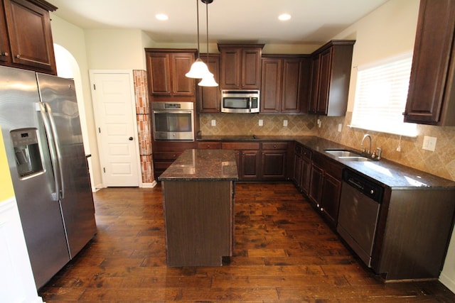 kitchen featuring a sink, decorative backsplash, a kitchen island, and appliances with stainless steel finishes