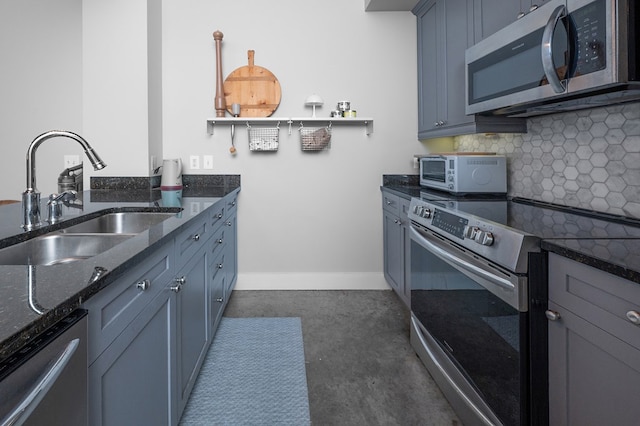 1201 Front Ave Unit 419, Columbus, GA 31901 - kitchen with stainless steel appliances, a sink, backsplash, dark stone countertops, and baseboards