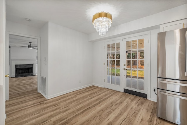 4975 Glacier Dr, Columbus, GA 31907 - unfurnished dining area featuring french doors, light wood-style floors, a ceiling fan, a fireplace, and a chandelier