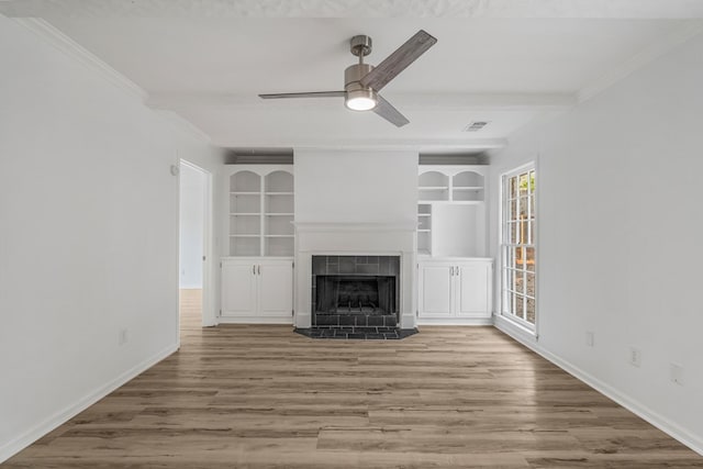 4975 Glacier Dr, Columbus, GA 31907 - unfurnished living room with a ceiling fan, a tiled fireplace, wood finished floors, crown molding, and built in features