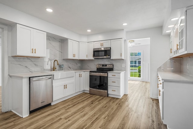 4975 Glacier Dr, Columbus, GA 31907 - kitchen featuring appliances with stainless steel finishes, light wood-style flooring, white cabinets, decorative backsplash, and recessed lighting