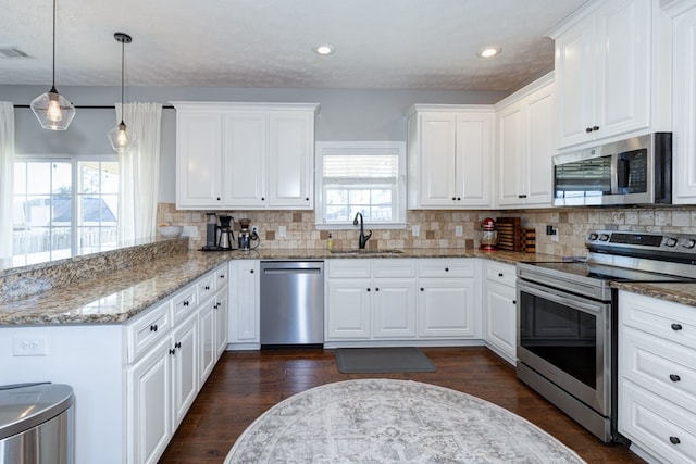 kitchen featuring decorative backsplash, sink, white cabinetry, hanging light fixtures, and appliances with stainless steel finishes