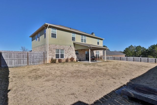 rear view of house featuring a lawn and a patio