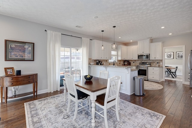 dining area with dark wood-type flooring, sink, and a textured ceiling