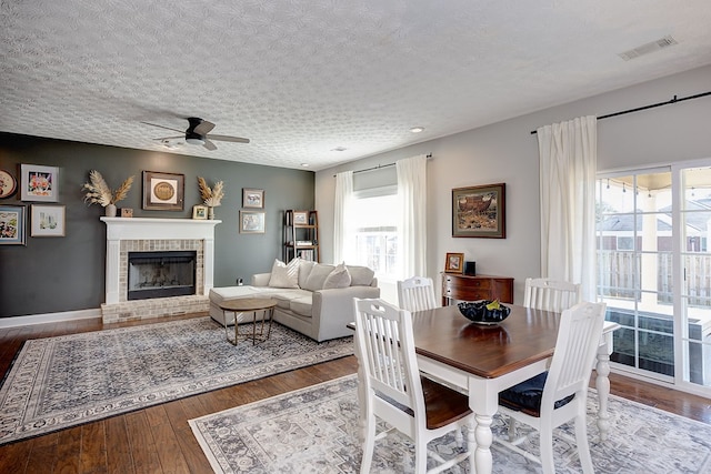 dining room with ceiling fan, plenty of natural light, a textured ceiling, and a fireplace