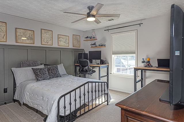 carpeted bedroom featuring ceiling fan and a textured ceiling