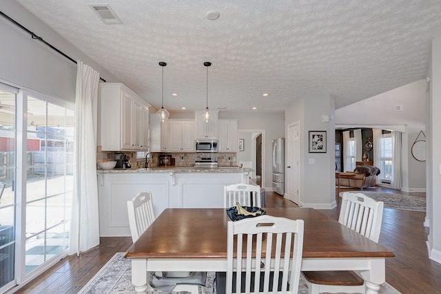 dining room with a textured ceiling, dark hardwood / wood-style flooring, and sink