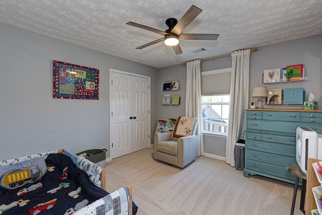 carpeted bedroom featuring ceiling fan, a closet, and a textured ceiling