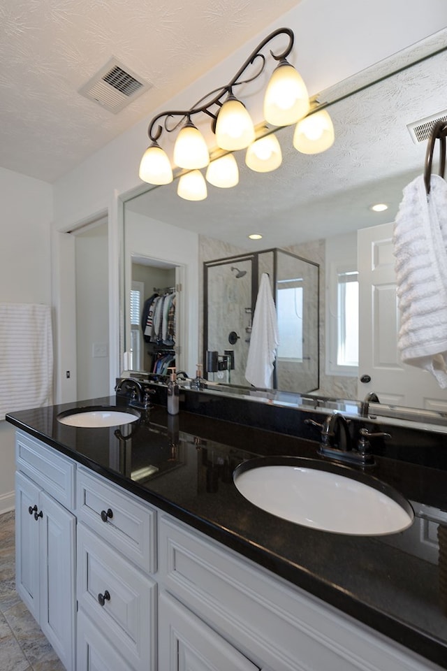 bathroom featuring walk in shower, vanity, and a textured ceiling