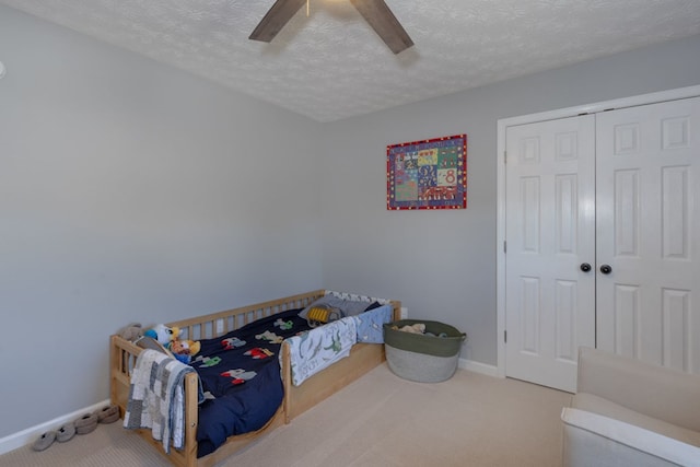 carpeted bedroom with ceiling fan, a textured ceiling, and a closet